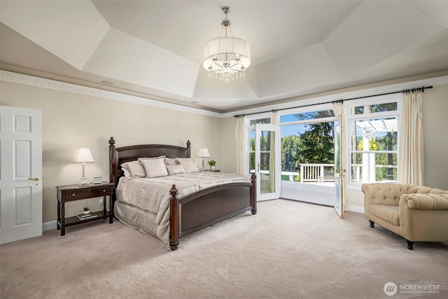 bedroom featuring access to outside, light carpet, a tray ceiling, and an inviting chandelier