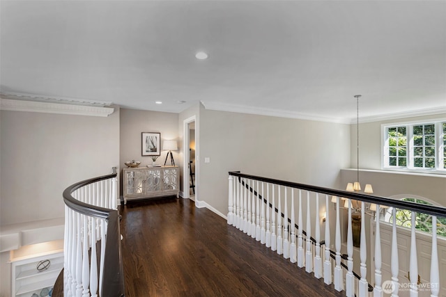 corridor with recessed lighting, wood finished floors, an upstairs landing, baseboards, and ornamental molding