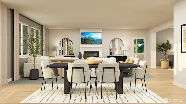 dining area with a glass covered fireplace, light wood-style flooring, and baseboards