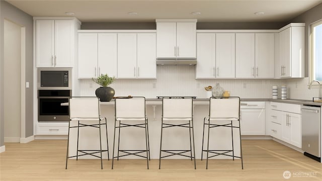 kitchen featuring stainless steel appliances, a center island, white cabinetry, and a kitchen breakfast bar