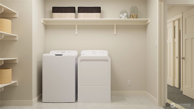 clothes washing area featuring laundry area, baseboards, and washing machine and clothes dryer