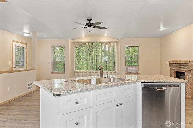 kitchen with light wood finished floors, a sink, plenty of natural light, and stainless steel dishwasher