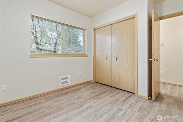 unfurnished bedroom featuring a closet, visible vents, baseboards, and wood finished floors