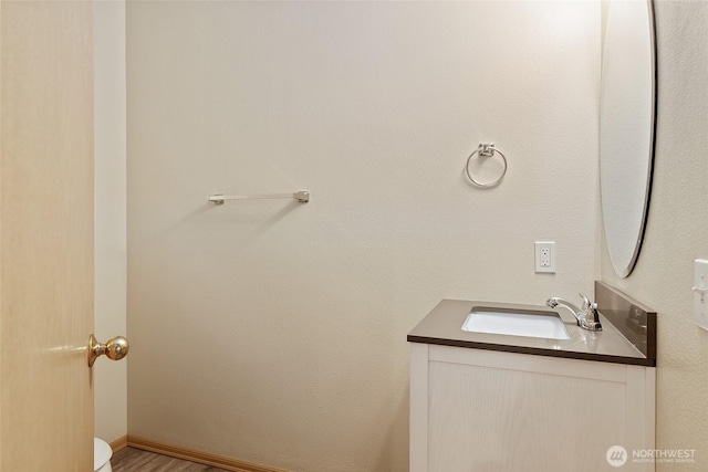 bathroom featuring baseboards, wood finished floors, and vanity