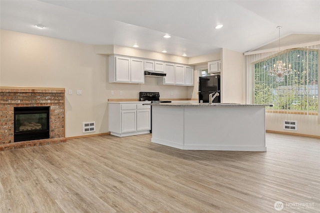 kitchen with visible vents, light wood-type flooring, black appliances, under cabinet range hood, and lofted ceiling