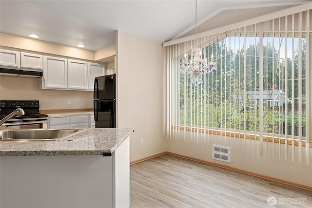 kitchen with a sink, black appliances, vaulted ceiling, light wood-style floors, and white cabinetry