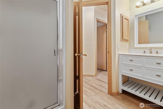 bathroom with a shower with door, wood finished floors, and vanity