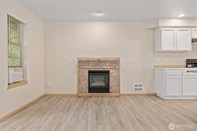 unfurnished living room featuring visible vents, cooling unit, baseboards, and light wood-style flooring