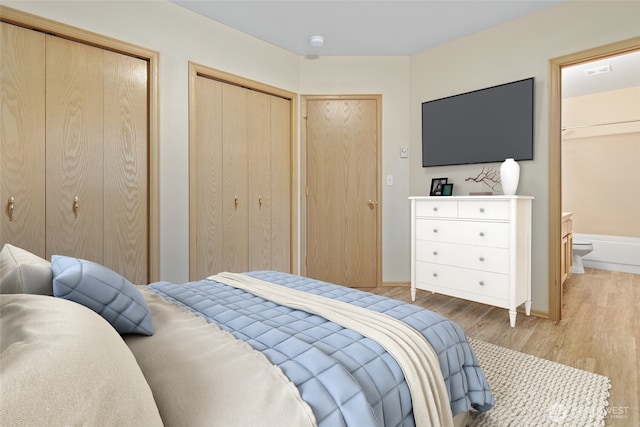 bedroom with visible vents, connected bathroom, two closets, baseboards, and light wood-type flooring