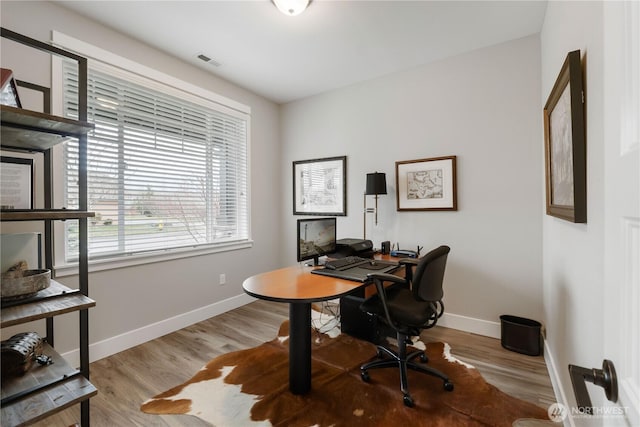 home office featuring wood finished floors, visible vents, and baseboards