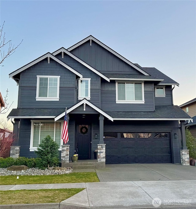 craftsman-style home featuring a garage, driveway, board and batten siding, and roof with shingles