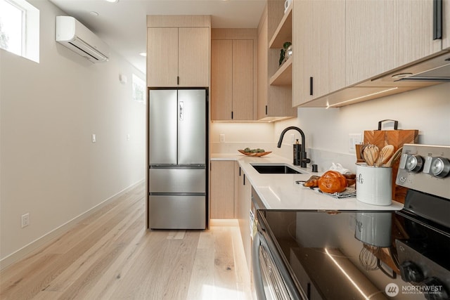 kitchen featuring appliances with stainless steel finishes, light countertops, an AC wall unit, light brown cabinetry, and a sink