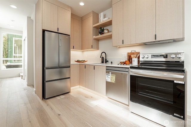 kitchen with light brown cabinets, a sink, light wood-style floors, appliances with stainless steel finishes, and open shelves