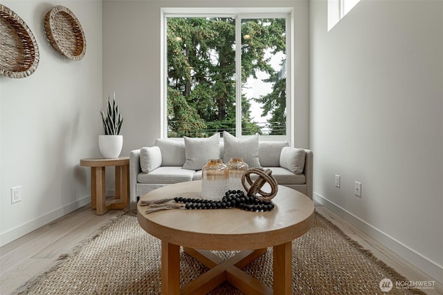 living area featuring baseboards, a healthy amount of sunlight, and light wood finished floors