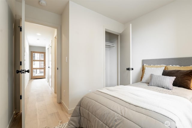 bedroom featuring light wood-style floors, baseboards, and a closet