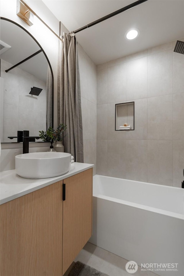 bathroom with visible vents, vanity, and shower / bath combo with shower curtain