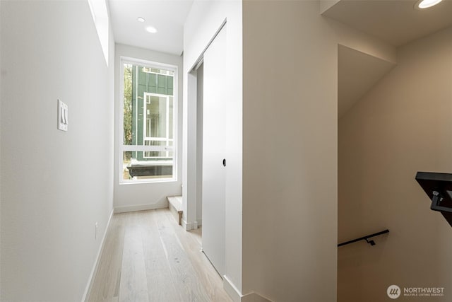 corridor with light wood-type flooring, baseboards, and recessed lighting