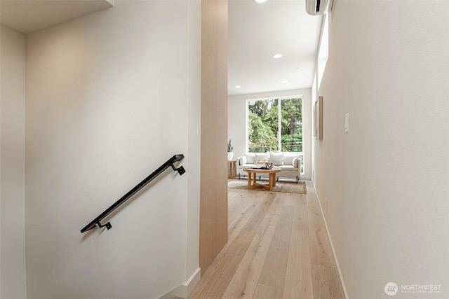 corridor with light wood-style floors, recessed lighting, baseboards, and an upstairs landing