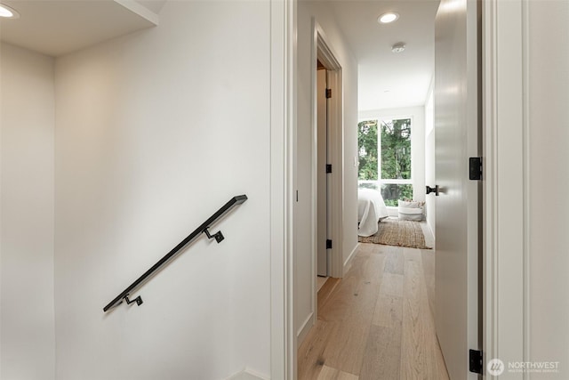 corridor featuring light wood-style floors, recessed lighting, and an upstairs landing