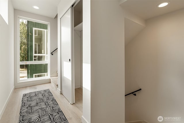 hall with baseboards, light wood-style flooring, and recessed lighting