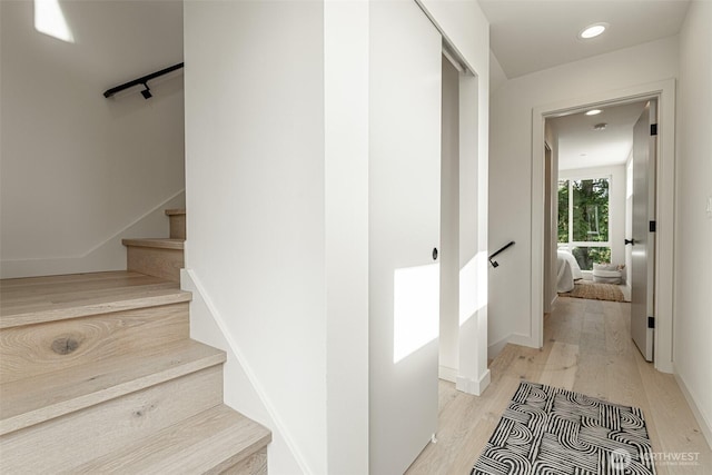 stairs featuring wood finished floors and recessed lighting