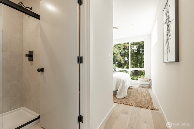 ensuite bathroom featuring wood finished floors, ensuite bath, a shower stall, and baseboards