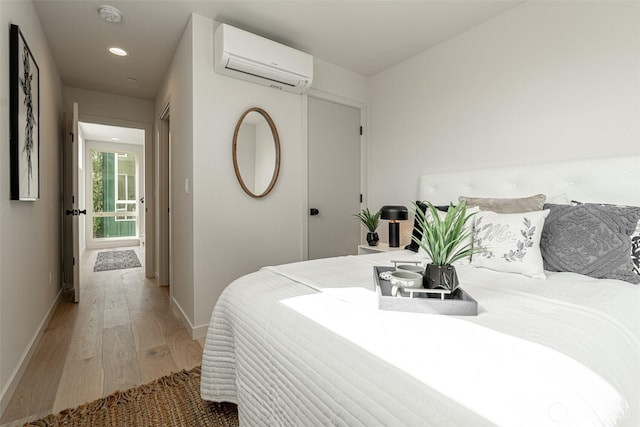 bedroom with light wood-type flooring, recessed lighting, baseboards, and a wall mounted AC