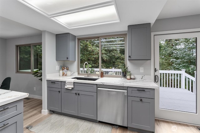 kitchen with gray cabinets, dishwasher, light wood-type flooring, and a sink