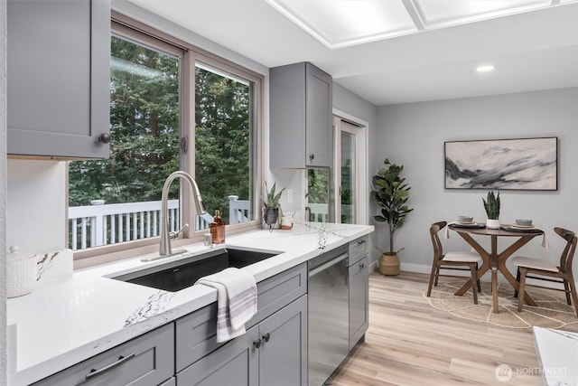 kitchen featuring a sink, dishwasher, gray cabinets, and light wood finished floors