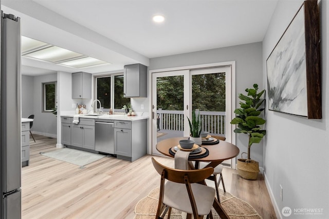 kitchen featuring baseboards, gray cabinets, light countertops, light wood-style floors, and appliances with stainless steel finishes