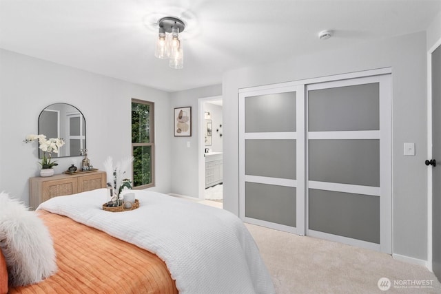 bedroom with light colored carpet, a closet, and ensuite bathroom