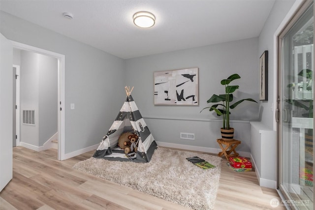 recreation room with visible vents, baseboards, and wood finished floors