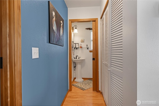 corridor with baseboards and light wood-style floors