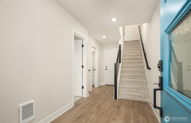 hall with light wood-type flooring, recessed lighting, baseboards, and stairs