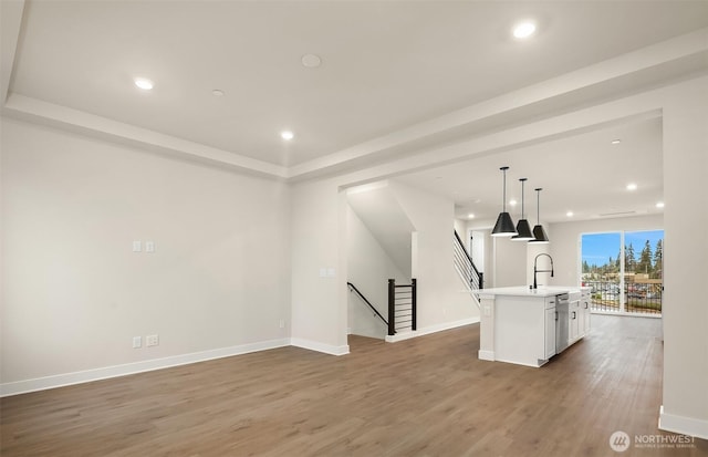 unfurnished living room featuring a sink, baseboards, wood finished floors, and recessed lighting