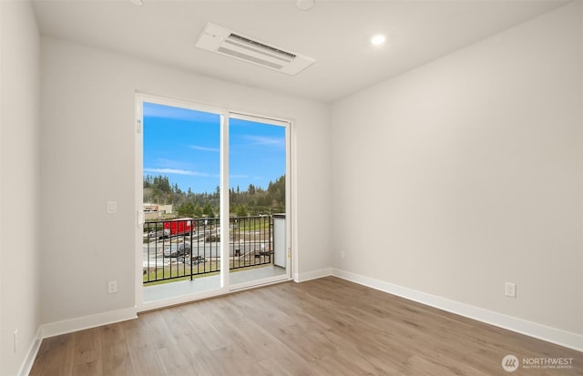 empty room featuring wood finished floors, visible vents, and baseboards