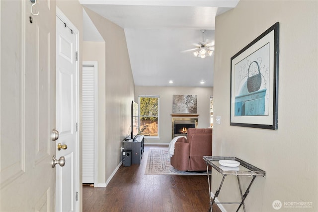 entryway with a warm lit fireplace, baseboards, dark wood finished floors, ceiling fan, and recessed lighting