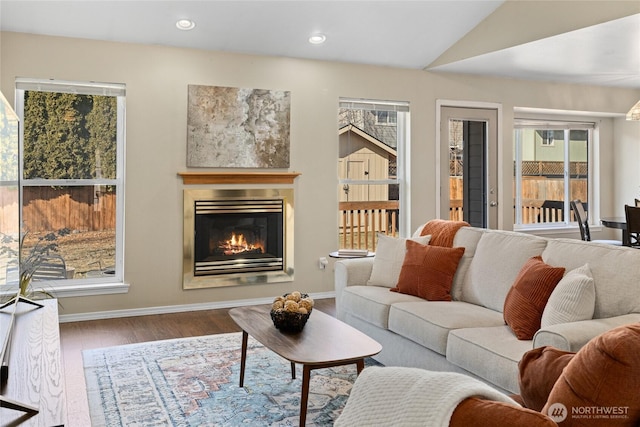 living area with lofted ceiling, recessed lighting, wood finished floors, baseboards, and a glass covered fireplace