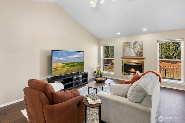 living room featuring lofted ceiling, a glass covered fireplace, dark wood finished floors, and baseboards