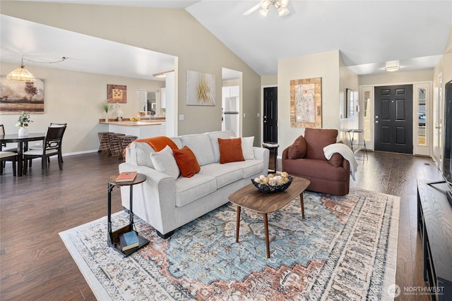 living area with dark wood-style floors, lofted ceiling, and baseboards