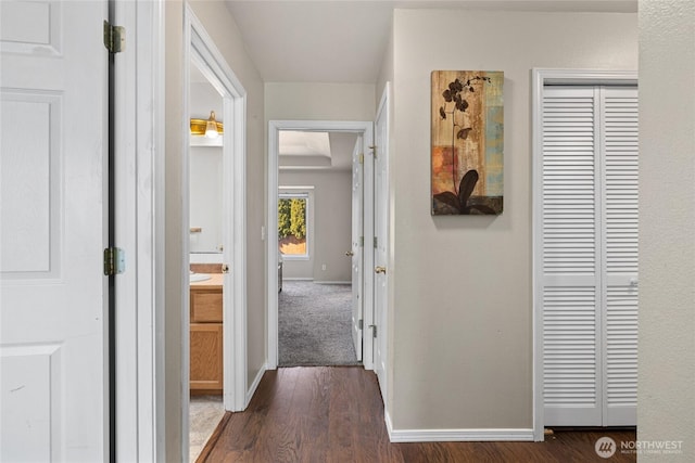 hallway featuring dark wood-type flooring and baseboards