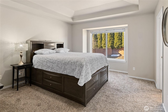 bedroom with light carpet, baseboards, and a tray ceiling