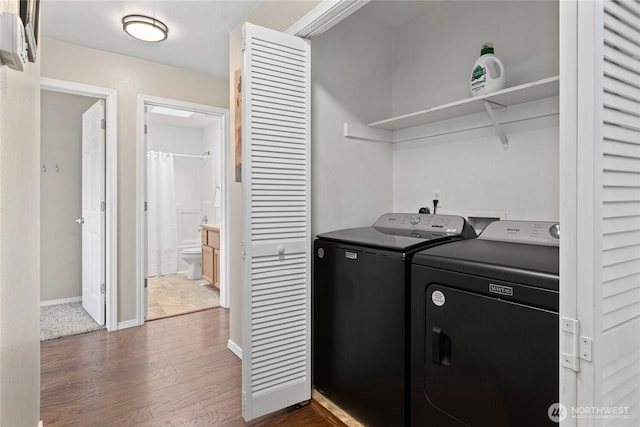 washroom featuring laundry area, baseboards, separate washer and dryer, and dark wood-style flooring