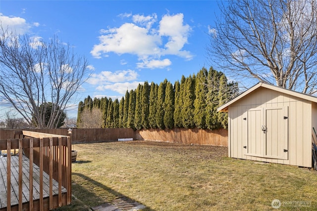 view of yard with a fenced backyard, an outdoor structure, a deck, and a storage unit