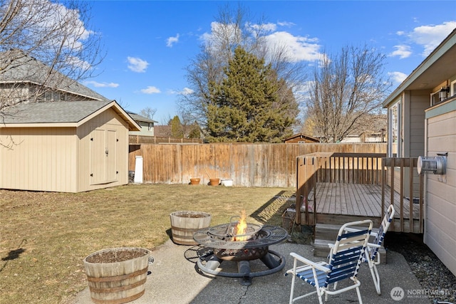 view of yard with a storage shed, an outdoor fire pit, a fenced backyard, an outbuilding, and a wooden deck