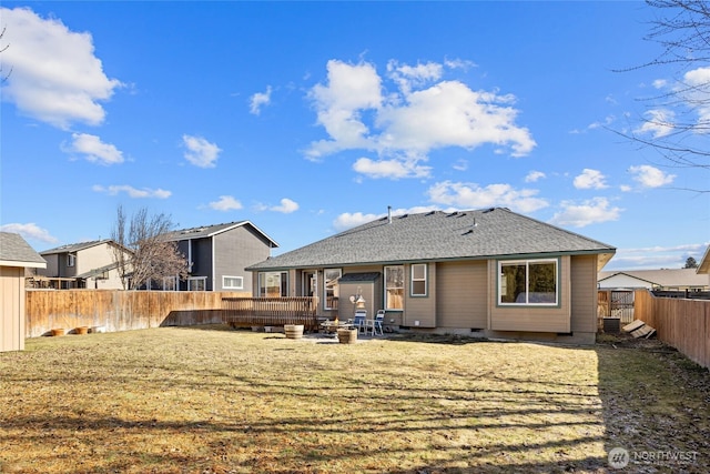 back of property featuring a fenced backyard, a fire pit, a shingled roof, crawl space, and a lawn