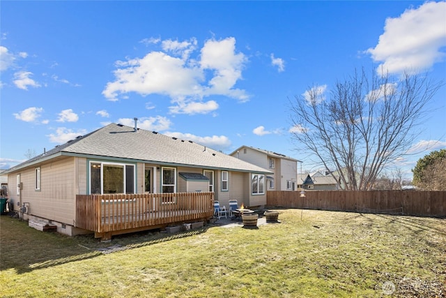 rear view of property featuring a fire pit, a lawn, roof with shingles, fence, and a deck