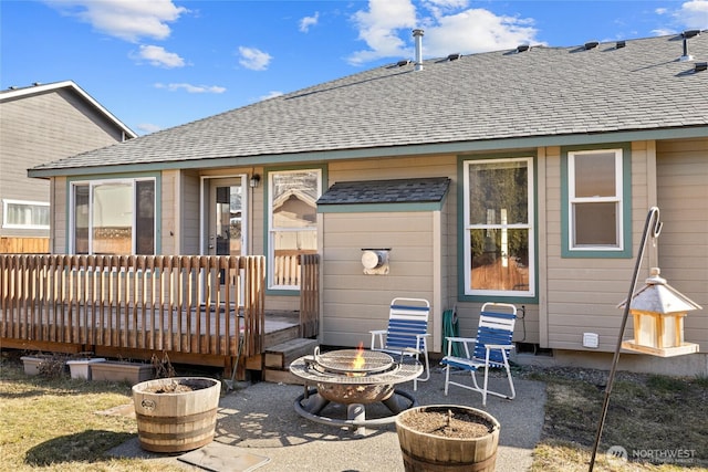 back of house featuring a patio area, an outdoor fire pit, a shingled roof, and a wooden deck