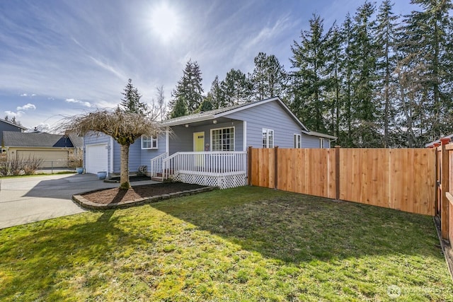 view of front facade with covered porch, a detached garage, fence, driveway, and a front lawn