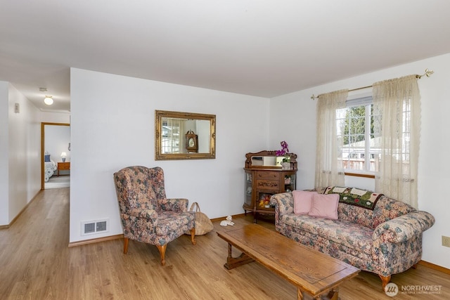 living area featuring visible vents, baseboards, and wood finished floors